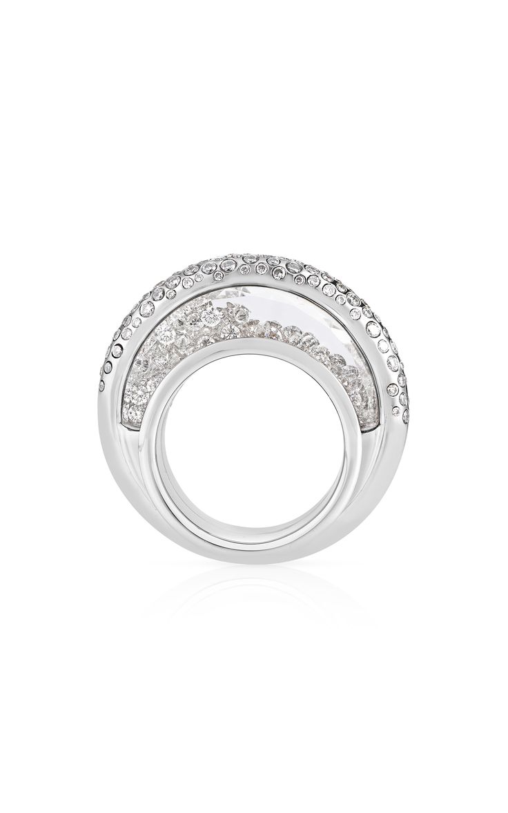this is a closeup of a silver ring with a clear crystal center. the ring is adorned with small crystals all over the outside of the ring, making the ring look very sparkly. the ring is placed against a white background.