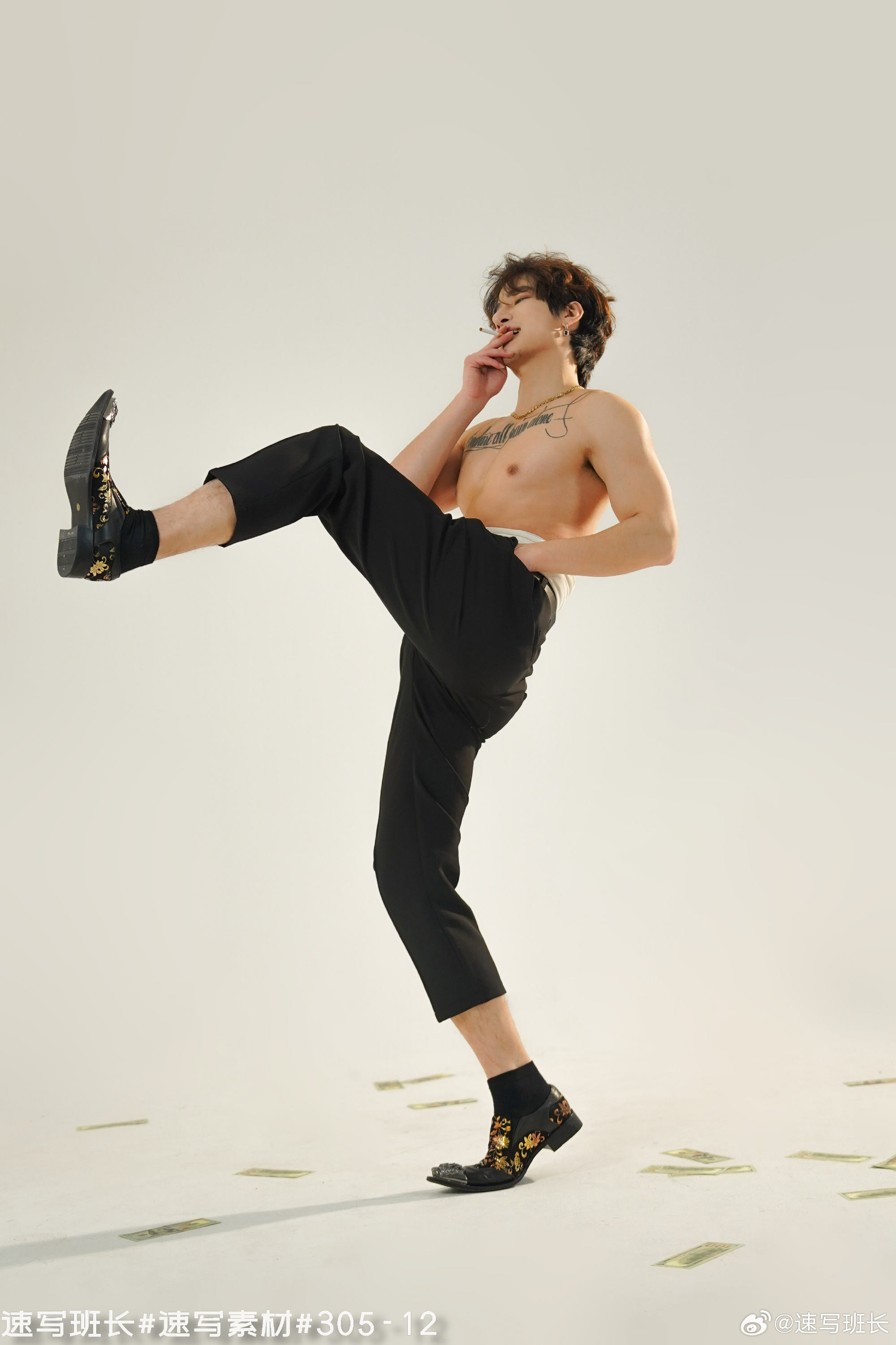 a shirtless man with tattoos on his chest and arms is striking a dynamic pose against a white backdrop. he wears black cropped pants and patterned loafers. he is surrounded by scattered paper money on the floor. the image appears to be a fashion photoshoot. the man has a cigarette between his lips and is gazing downwards. the overall image suggests a rebellious and confident attitude.