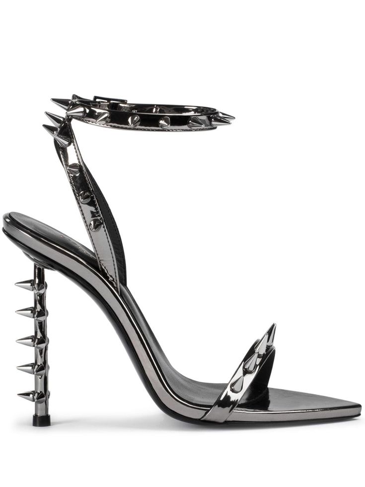 a pair of women's highheeled sandals with a pointed toe. the shoes are made of gunmetalcolored metallic leather and feature a thin ankle strap and multiple spikes along the strap and heel. the shoes are positioned on a white background.