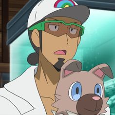 a closeup of a man with tanned skin, dark brown hair tied in a low ponytail, and a short beard. he is wearing a white baseball cap with a rainbowcolored bill and greentinted sports glasses. he's wearing a white shirt with a visible collar. he appears surprised or in disbelief, with his mouth slightly open and eyebrows raised. he is holding a brown and creamcolored pokémon that resembles a dog with large blue eyes. the background suggests an indoor setting with a blurred blue and green aquarium visible behind him.