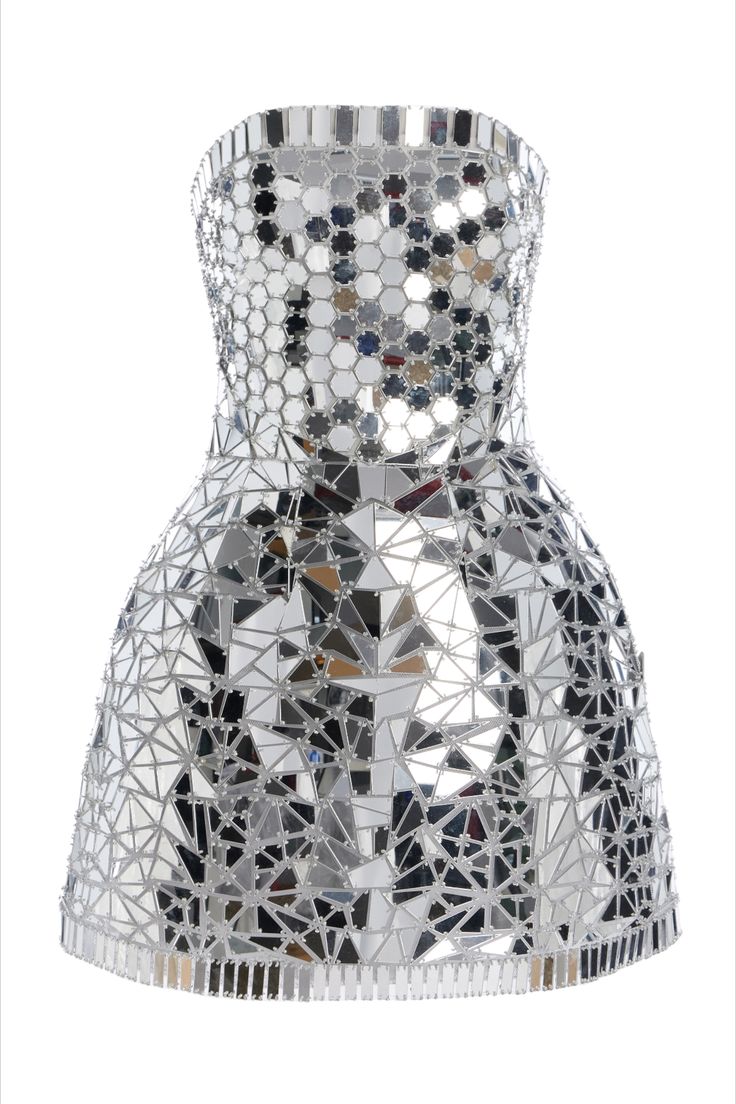 a strapless mini dress is covered in mirrored tiles of varying shapes, including hexagons on the bodice and triangles on the skirt. the tiles are silver, and reflect light, creating a dazzling effect. the dress is on a white background.