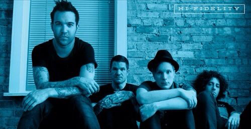 a band of four young men are sitting together in a room, looking at the camera. they are all wearing casual clothing and have their hair styled in a modern way. the man on the left is wearing a black shirt and jeans, while the man on the right is wearing a black shirt and jeans. the two men in the middle are wearing shirts and jeans. the band name "hi fidelity" is written in large letters at the top of the image. the band is likely a rock or punk band, as they have a modern look and style. the image could be an album cover or a promotional photo for the band.