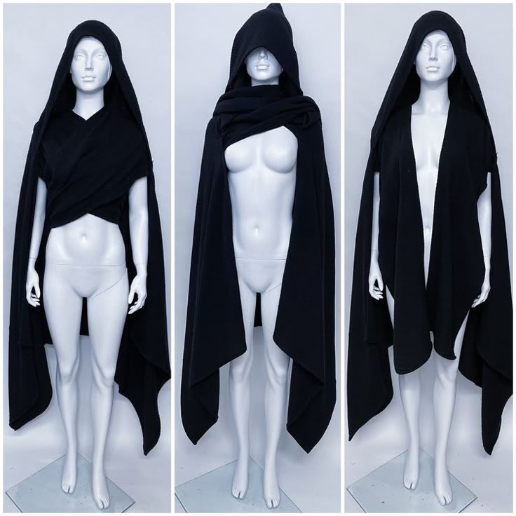 the image shows three mannequins wearing the same black, hooded cloak draped in different styles. the mannequins are standing in a studio setting with a lightcolored background. the left mannequin has the cloak wrapped and crossed in the front. the center mannequin has the cloak pulled up and wrapped around the neck. the right mannequin wears the cloak open in the front.