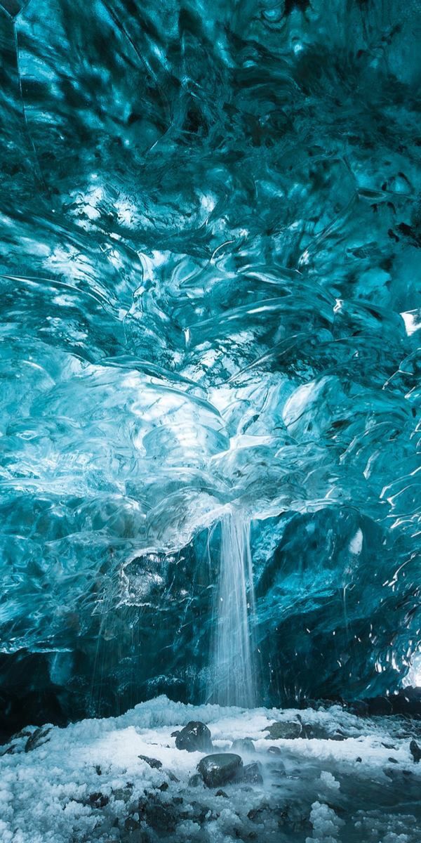 an ice cave with a waterfall flowing into a snowy landscape. the cave's texture is icy blue, creating a cold and frozen atmosphere.