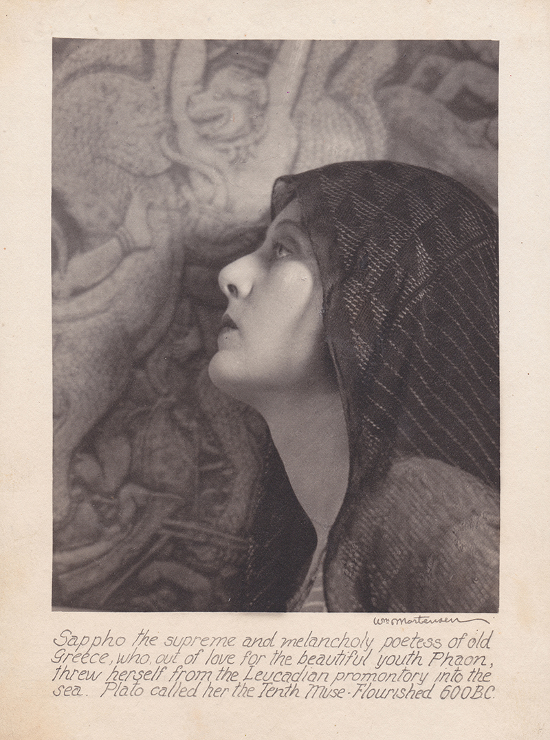 a black and white vintage portrait photograph by william mortensen depicts a woman, possibly portraying sappho, the ancient greek poetess, veiled and looking upward with a melancholic expression. the background features a blurred, textured image suggestive of classical greek art or architecture. the photograph is accompanied by a caption providing biographical information about sappho, mentioning her tragic end and plato's reference to her as the tenth muse. the style is reminiscent of pictorialist photography.