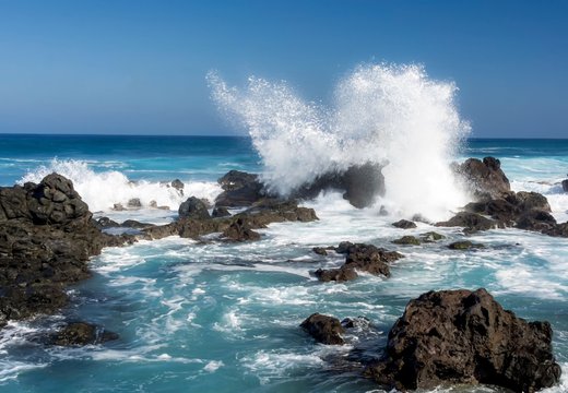a beautiful shot of the ocean with waves crashing on the rocks. the white sea foam creates a beautiful contrast against the blue water.