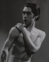 a black and white closeup photograph of a muscular man, possibly a dancer, with his torso bare. he is posed with one arm across his chest, his expression is serious and contemplative. the lighting is dramatic, creating strong shadows and highlighting his physique. the overall style is classic and vintage, possibly from a mid20thcentury photoshoot.