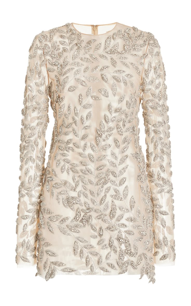 a closeup studio shot features an ivory, longsleeved mini dress adorned with a leaves pattern. the dress has a sheer beige fabric base, and the intricate leaves pattern is embellished with silver beads.