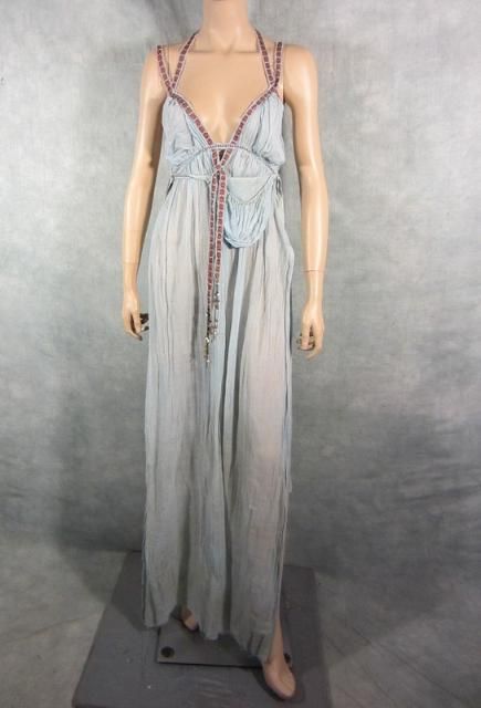 a light blue halter top maxi dress is displayed on a mannequin. the dress features intricate detailing around the neckline and bodice, leading down to a flowing skirt. the mannequin stands against a grey background.