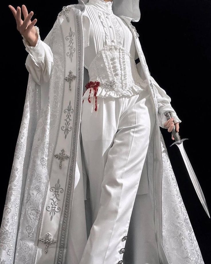 a person wearing a white cape with silver trim and intricate detailing, paired with white pants and a white shirt with a corset, holding a silver sword. the person is standing in a dark environment, highlighting the elegance and sophistication of their attire.