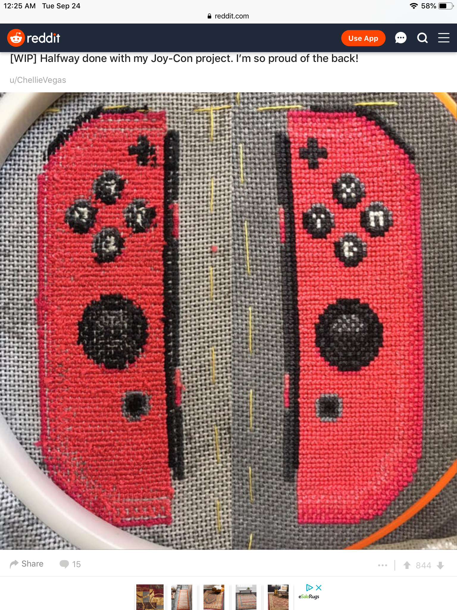 a closeup of a crossstitch project depicting a red nintendo switch joycon controller. the stitch is mostly complete, leaving only the space between the controllers unfilled. the photo is taken at an angle, showing the slightly raised stitch against the white background. the background is out of focus.