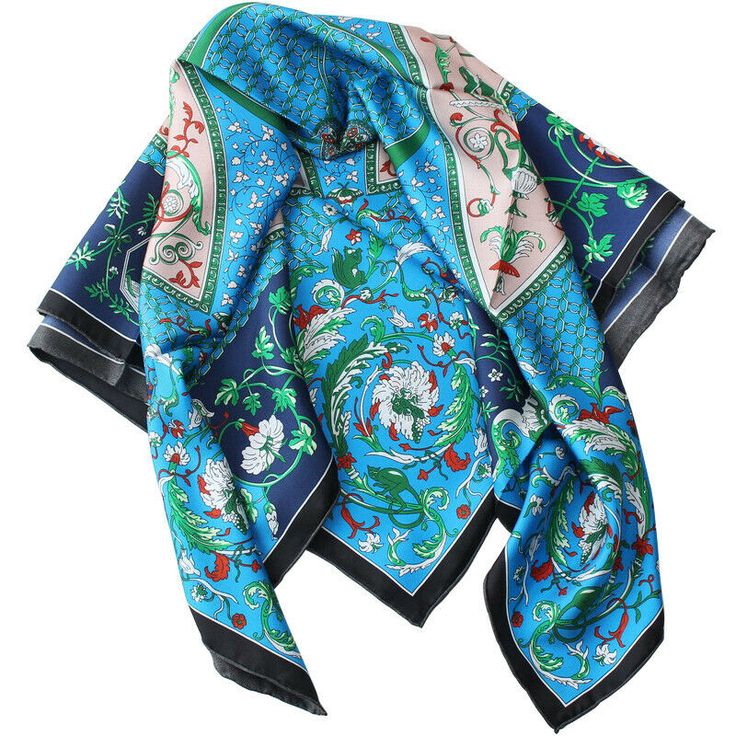 a close up of a colorful silk scarf in a vibrant floral pattern. the scarf is blue with green and red paisleylike designs, and has a square shape. the fabric is soft and flowing. it's a perfect accessory to add a touch of style to any outfit.