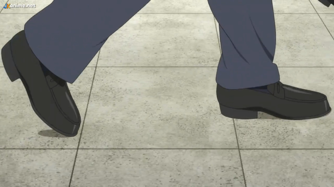 a closeup shot of a man's legs as he walks across a tiled floor. the man is wearing black dress shoes and dark blue trousers. the camera angle is low, capturing the movement of the feet and the texture of the tiles. the lighting is bright and even, highlighting the details of the scene.