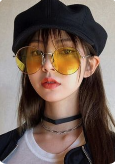 a closeup portrait of a young woman wearing a black beret, yellowtinted round sunglasses, a black choker, and a silver chain. she has long dark hair with bangs, and is wearing coral lipstick. she is wearing a white shirt and a black jacket. the image is a selfie taken indoors with soft lighting.