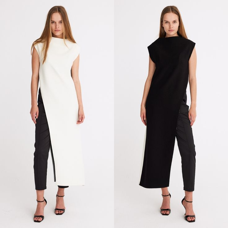 two women are standing sidebyside, posing in a studio shot. the woman on the left is wearing a white dress with a high slit, revealing black pants underneath, paired with black high heels. the woman on the right is wearing a similar outfit, but in black. the dresses have a sleeveless design with a high neckline. the background is a plain white.