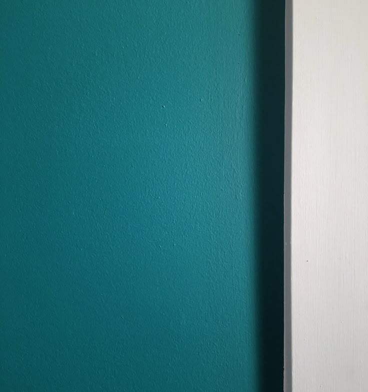 a closeup shot of a turquoise painted wall next to a white trim.