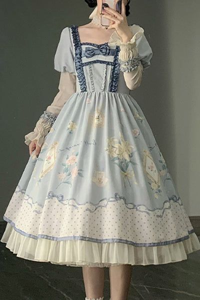 a woman poses in front of a mirror wearing a long, flowing, blue and white lolita dress. the dress has a square neckline, puffed sleeves, and is decorated with a floral pattern and lace accents. the woman is also wearing white tights and her hair is styled in a high ponytail.