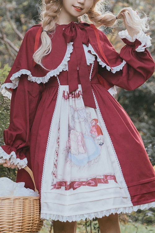 a woman in a red and white lolita dress stands in a forest. she is holding a basket in her left hand and her hair in her right hand. the dress has a red capelet, long sleeves with ruffles at the wrists, and a white skirt with a print of little red riding hood and the wolf. the dress is cinched at the waist with a red ribbon.