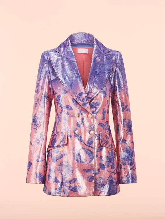 a doublebreasted blazer with a floral pattern is displayed against a plain peach background. the blazer features a gradient color scheme, transitioning from purple on the upper portion to pink on the lower half. the fabric appears to be shiny or metallic. the blazer has a lapel collar, long sleeves, and pockets, and is adorned with pearl buttons.