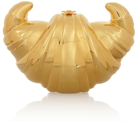 a golden croissantshaped clutch purse. the clutch is made of gold and has a shiny finish. it is a beautiful and unique accessory that would be perfect for a special occasion.