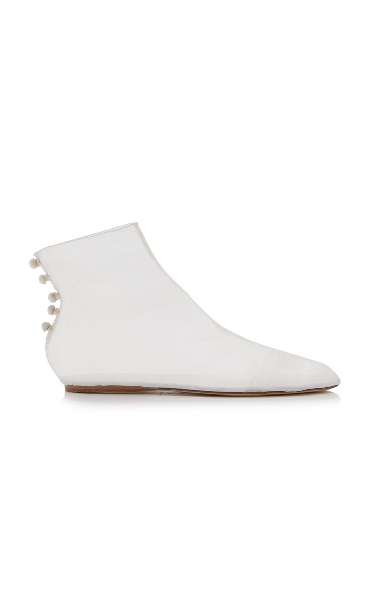 he image shows a pair of women's transparent white pvc ankle boots with a pearl detail on the back. the boots are flat and have a minimalist design. they appear to be made of a lightweight, flexible material. the background is plain white, allowing the shoes to be the focus.  the style is modern and contemporary.