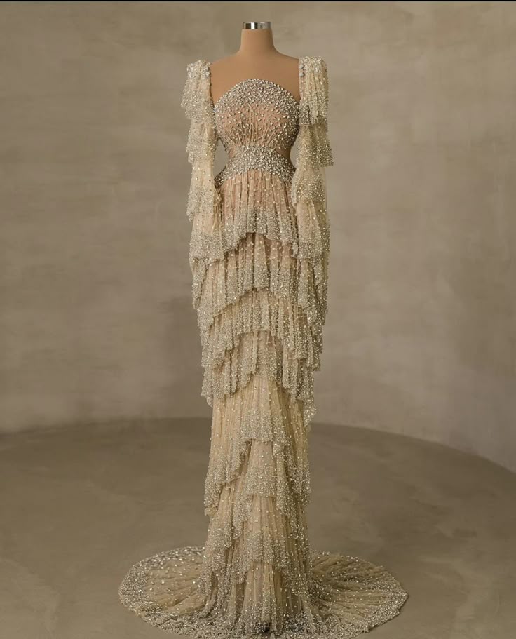 a long, formal evening gown is displayed on a mannequin. the gown features a strapless neckline, fitted bodice, and a tiered skirt. the entire gown is covered in beading.
