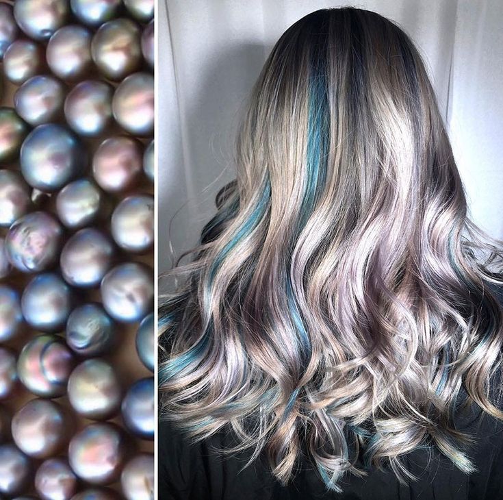 a woman with long wavy hair. her hair is a mix of grey and silver, with some blue streaks. she is looking to the side and her hair is styled in a way that shows off the layers and the highlights. the lighting is bright and the colors are vibrant.