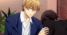 the image depicts a scene from an anime featuring a blondehaired man with sharp eyes looking intently at a darkhaired woman with her head down, seemingly upset. he's gently touching her back with a concerned expression. the setting suggests an intimate moment indoors, possibly in a home or office, with warm lighting creating a soft atmosphere. the overall composition emphasizes the emotional tension between the characters.
