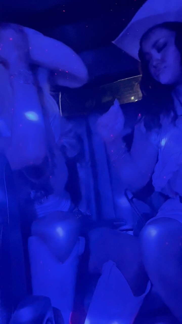 a bluetoned indoor image featuring a woman wearing a hat. the scene is dimly lit, possibly at night or in a darkened room, illuminated with blue light. it appears to be a party setting.