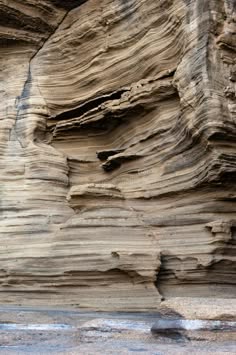 a close up of a layered rock formation, the layers are visible and distinct.  the rock is brown and grey, with a rough texture.  the layers are slightly angled, giving the rock a sense of movement.  the rock is weathered and eroded, suggesting that it is very old.  the rock is part of a cliff face.  this image is a great example of the beauty of nature and the power of geological forces.