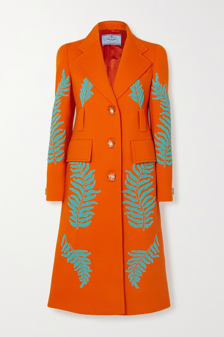 an orange prada coat with teal fern embellishments. the coat is a tailored, midlength design with two buttons at the front, two flap pockets on the chest, and teal fern patterns on the sleeves and front panels.