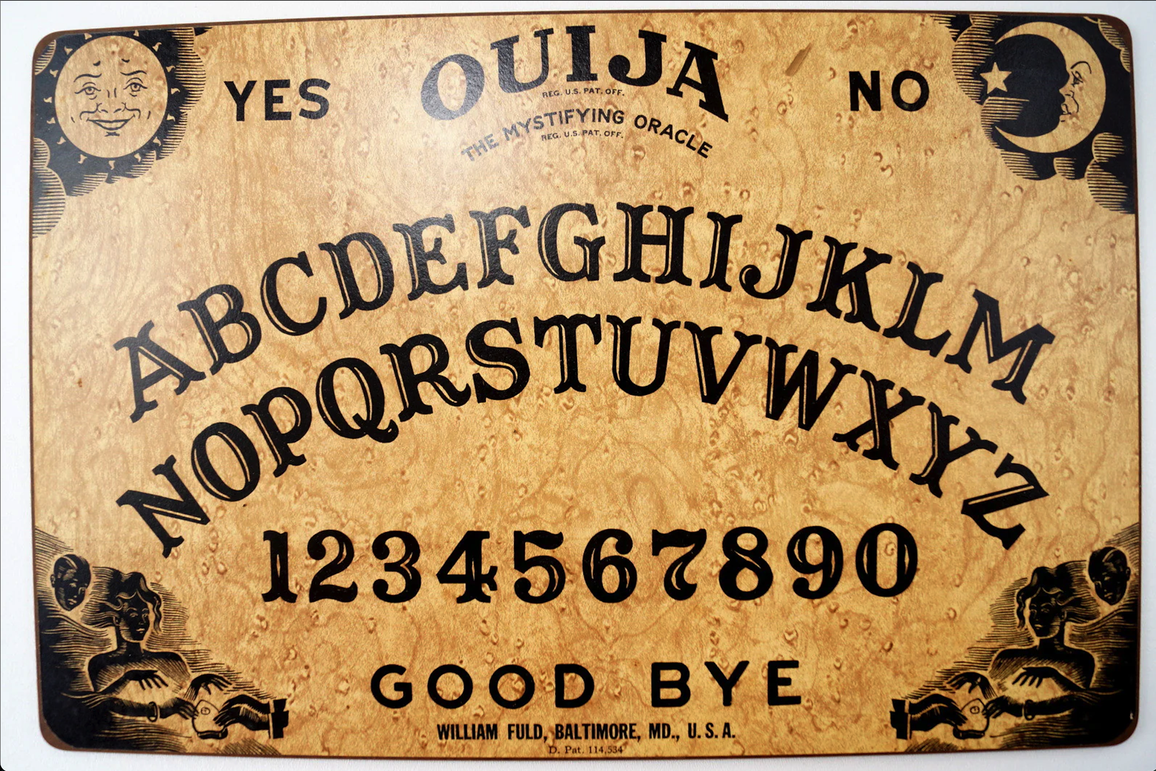 a vintage ouija board with a woodgrain background. it features the letters of the alphabet, numbers 19 and 0, along with the words "good bye", "yes", and "no". it also has two crescent moonshaped sections with stars in the corners.