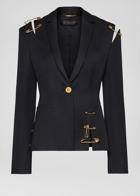 a black versace blazer with gold safety pin embellishments on the shoulders and sides. the blazer is buttoned at the waist and has a vneckline.