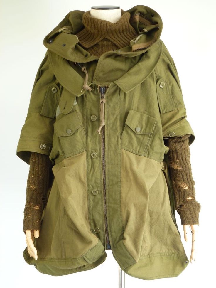 this is an image of a green militarystyle jacket with a large hood. it has long sleeves with distressed brown fabric on the sleeves. there are large pockets on the front of the jacket and the zipper is closed.