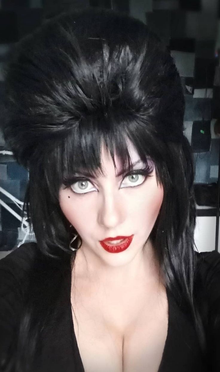 a woman with long black hair is dressed in a black outfit and has dark makeup on