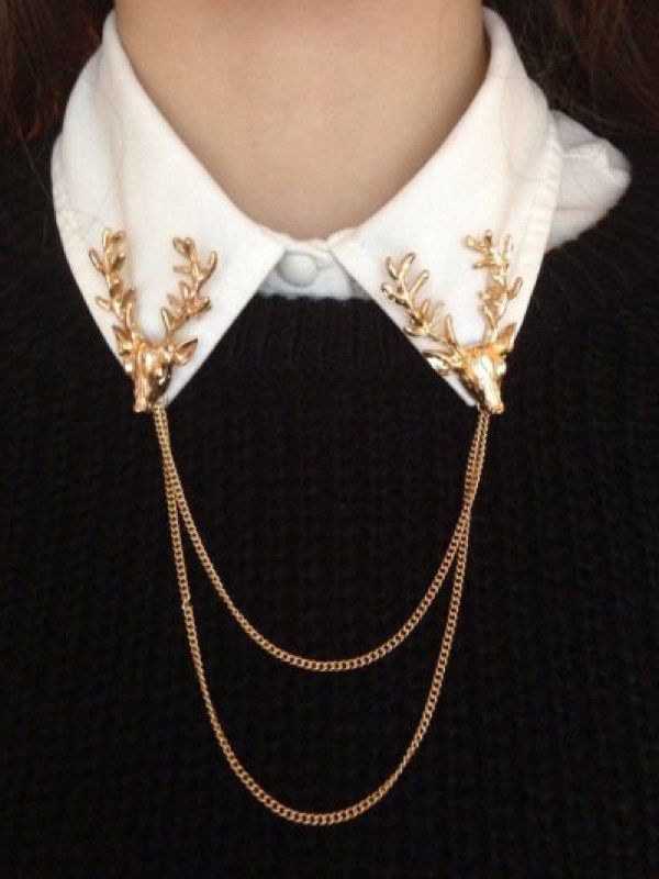 loseup view of a person wearing a stylish gold necklace featuring two deer antler charms that are pinned to a white collared shirt. the necklace is a double chain and hangs over a black sweater. the overall style is elegant and chic.
