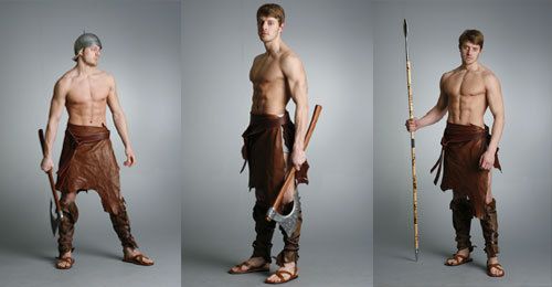 the image features three men dressed as warriors. the man on the left is wearing a helmet and holding an axe. the man in the middle is holding an axe and is wearing a leather loincloth. the man on the right is holding a spear and wearing a leather loincloth.  the image suggests an ancient setting, and the men appear to be warriors or barbarians.