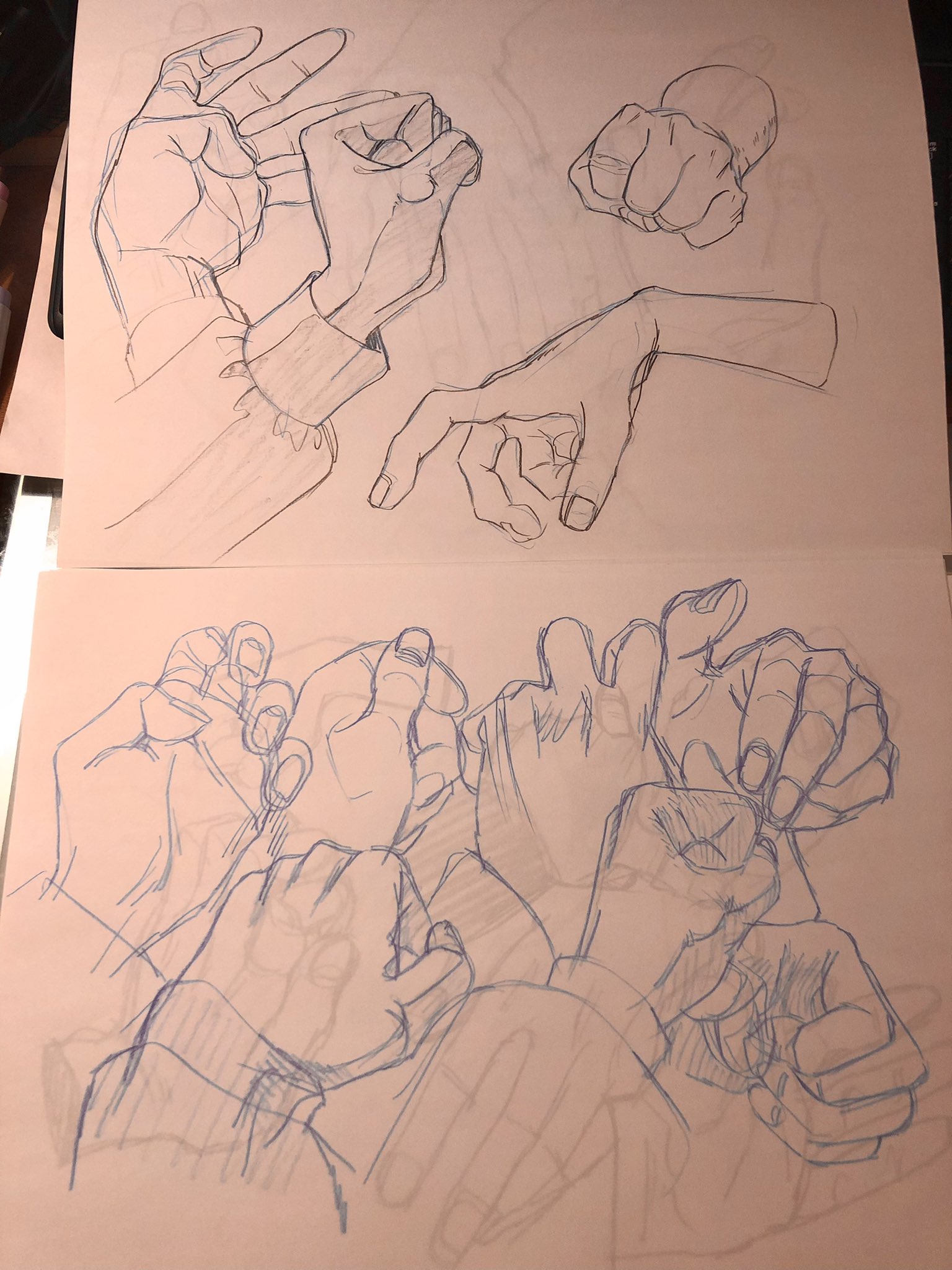 this is a picture of 2 pieces of paper with multiple sketches of hands in different positions. the paper is tan or pink, and the sketches are drawn in black and blue ink.  the sketches appear to be drawn with pencil first, and then outlined in pen.  they are from the wrist up, and are all different angles and positions.