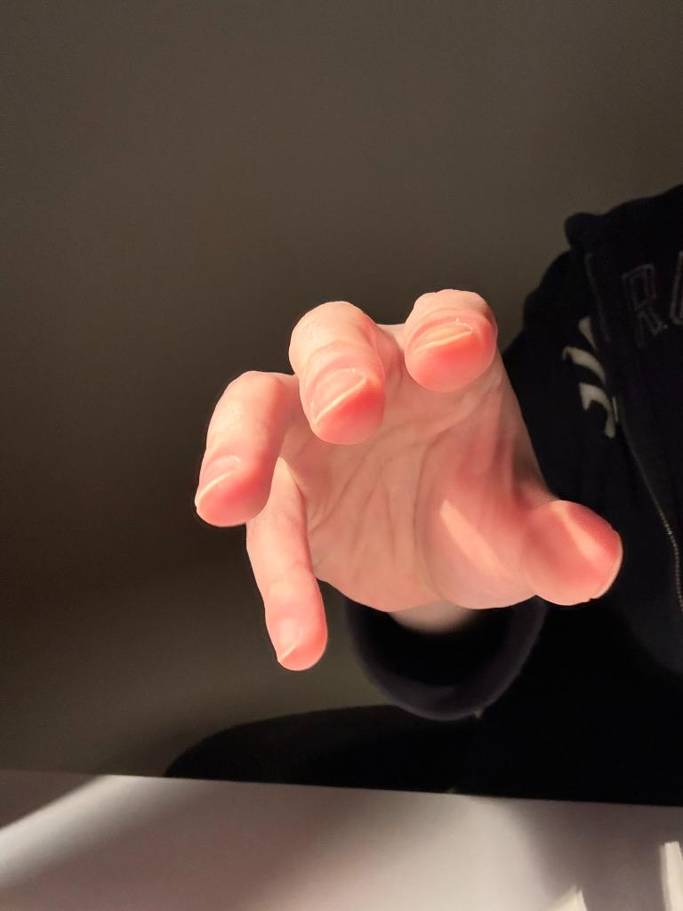 a single hand, fairskinned and with short fingernails, reaches forward toward the viewer. the hand is illuminated by warm, golden sunlight, suggesting a sunset. the person's black clothing can be seen in the background, but their face and surroundings are obscured.