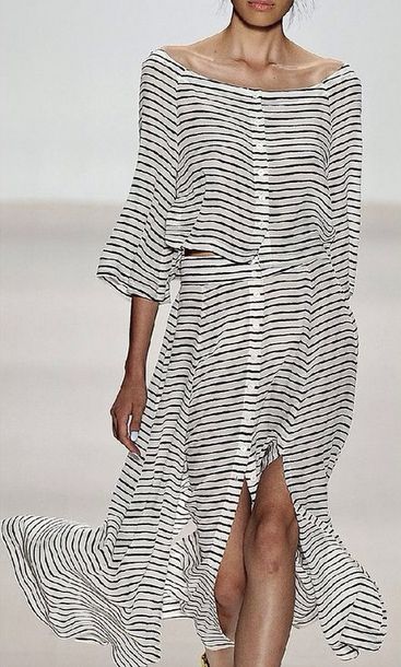 a model walks the runway wearing a stylish black and white horizontally striped maxi dress. the dress has a relaxed fit, long sleeves, a high slit, and a buttondown front. the model's pose and the flow of the dress emphasize the garment's details and texture. the background is a simple, white backdrop typical of fashion runway shows. the overall aesthetic is casual yet chic, suitable for summer.