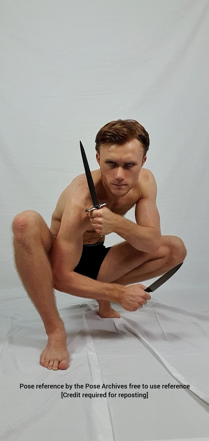 a man is sitting with his knees bent and holding a dagger in his left hand. his right hand is on the ground. he is looking at the camera. he is wearing underwear and has a toned physique. the background is white. the image is suitable for artists and designers as a pose reference.