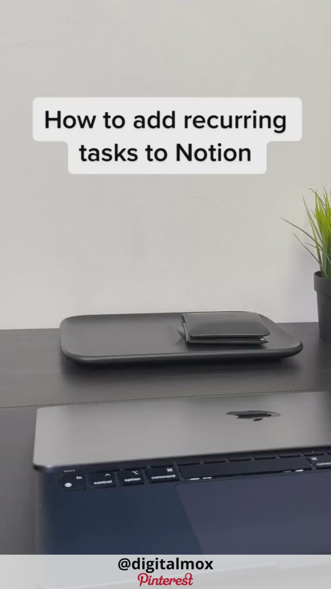 a closeup shot of a black laptop on a desk, a tray sits next to it. there is a text overlay that reads, "how to add recurring tasks to notion"  on top of the image. there is a plant on the right hand side of the image.  the laptop is open to a blank screen with a black keyboard. the text overlay is meant to be a title or a caption for a video on how to use notion.