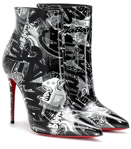 a pair of christian louboutin ankle boots are shown in a studio shot. the boots are black and white patent leather with a graffitistyle print covering the entire surface.  they feature a pointed toe and a very high, thin stiletto heel with the signature louboutin red sole visible at the bottom. the boots are angled slightly, showcasing both the front and side profiles. the background is plain white, ensuring the boots are the focus of the image.