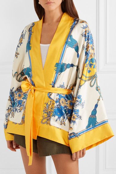 loseup shot of a woman wearing a stylish yellow and floral printed kimonostyle robe. the robe is made of silk or satin material, with wide sleeves and a matching yellow belt tied at the waist. the model is standing against a clean white background, showcasing the details of the garment, from the vibrant colors to the intricate print. the overall look is elegant and casual, suitable for spring or summer wear.