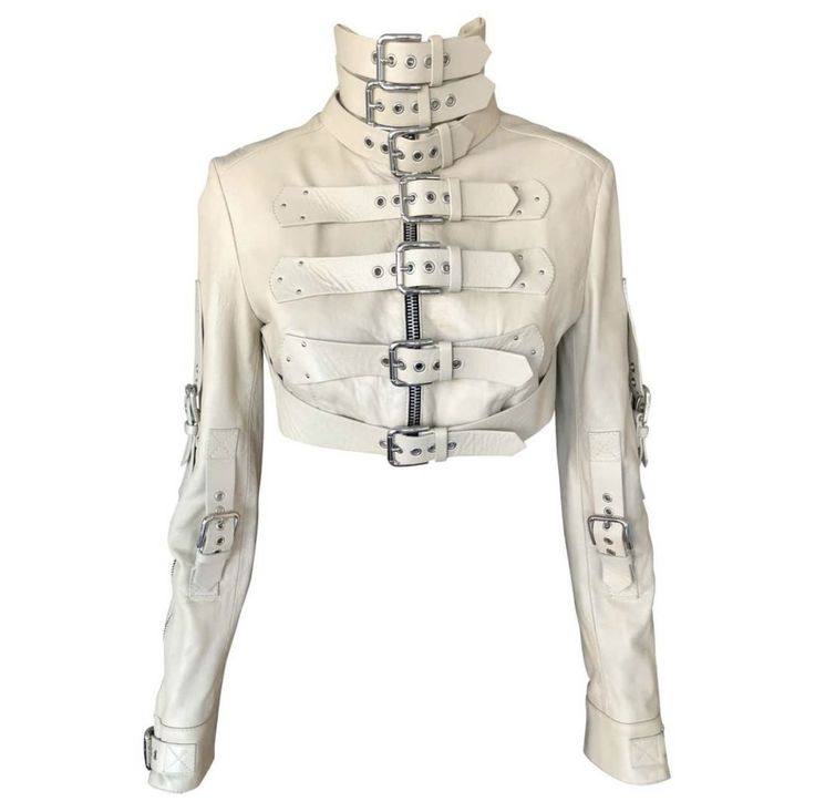 a white leather jacket with multiple straps and buckles, including a high collar and cropped length. the jacket features a zipper closure and long sleeves. it is a unique and stylish piece of clothing that is sure to turn heads.