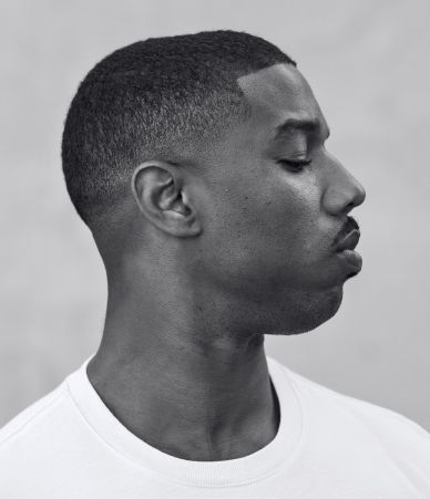 a black and white portrait of michael b. jordan in profile. he has a short haircut and is wearing a plain white tshirt.