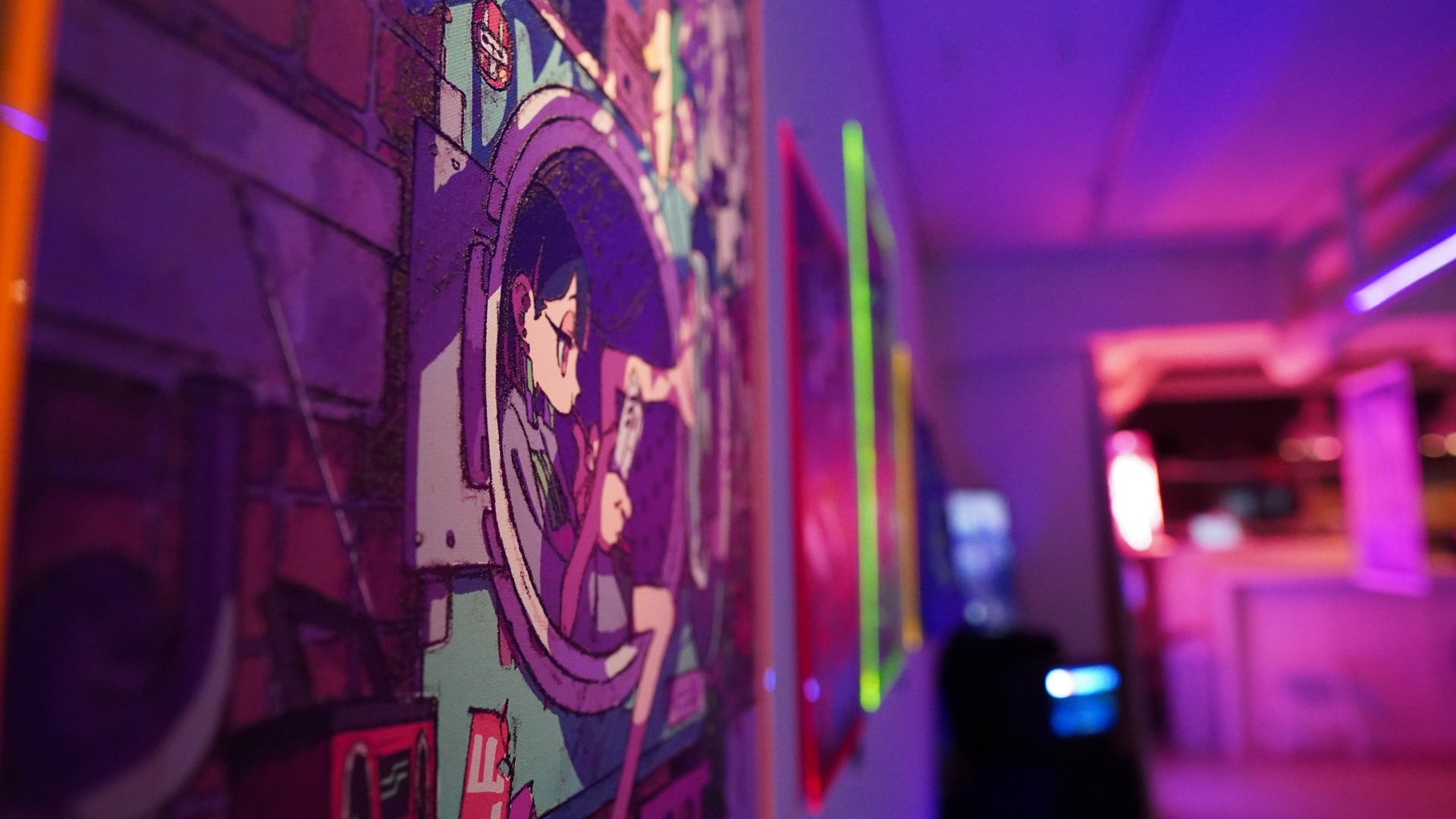 the image showcases a closeup view of colorful artwork, likely in a gallery or exhibition space. the artwork features an animestyle female character and incorporates a vibrant color palette with neon accents.  the shallow depth of field draws focus to the art piece, while the background hints at a larger, potentially cyberpunkinspired setting.