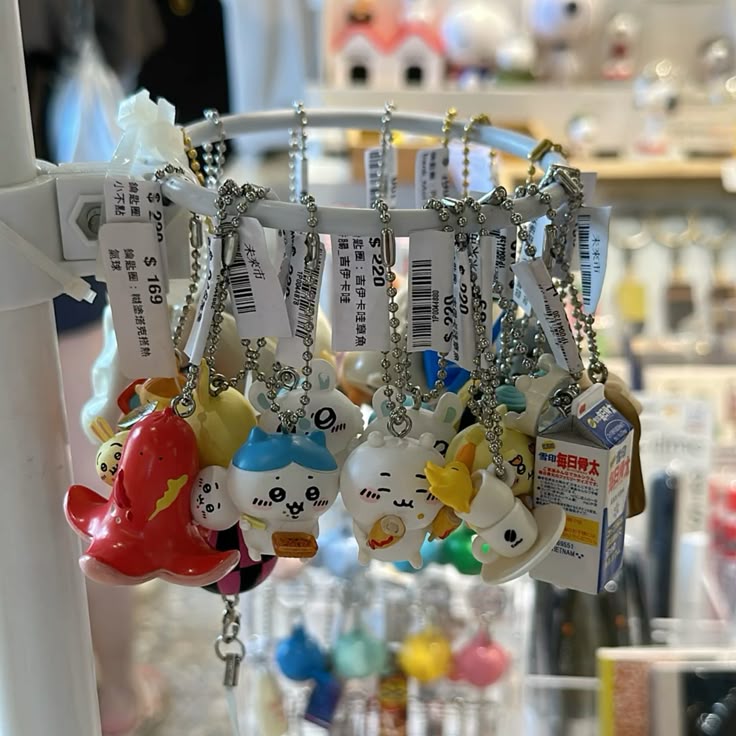 a closeup shot features a collection of cartoon character keychains hanging from a circular metal rack. the keychains are various characters, including an octopus and a milk carton. each keychain has a price tag attached. the background shows a store setting with other merchandise.