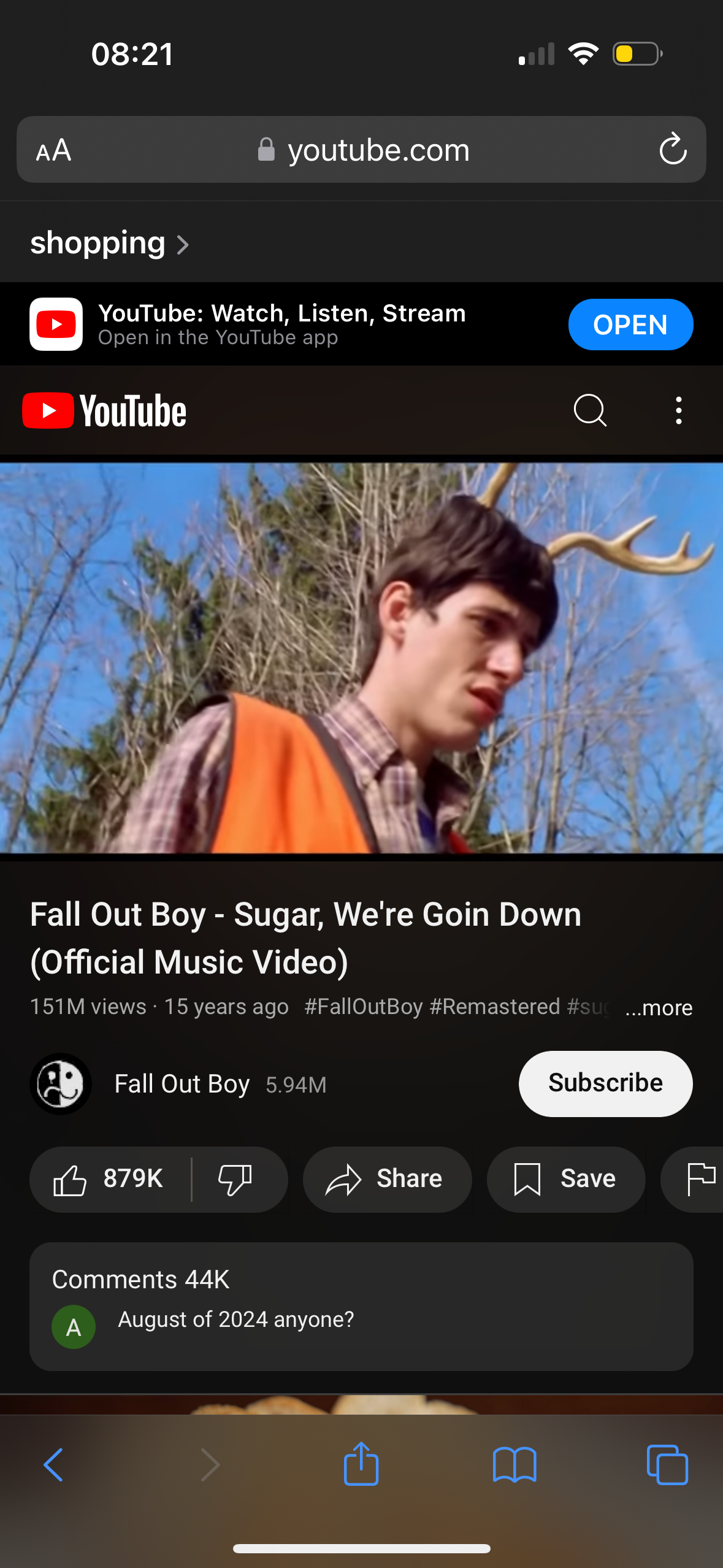 this is a screenshot of a youtube video on a mobile phone. the video is for the song "sugar, we're goin down" by the band fall out boy. the video has 151 million views and was uploaded 15 years ago. the video is labeled as remastered. the screen also shows that the band has 5.94 million subscribers, the video has 879k likes, and 44k comments. the comment section shows a comment asking if anyone remembers august of 2024. the image also includes the youtube app controls, such as buttons to share, save, subscribe, and the back button. the video thumbnail shows the lead singer of the band in a hunter's outfit, standing in the woods. he is wearing a camouflage shirt and a hunter's vest, and he has antlers on his head. the background shows trees and a green field.