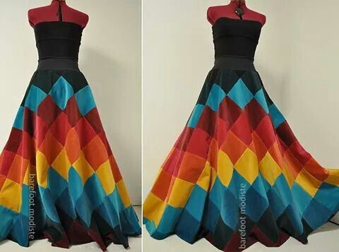 the image shows two mannequins wearing identical dresses. the dresses have a black sleeveless top and a long, flowing skirt made of colorful patchwork diamonds in shades of red, yellow, and blue. the text "barefoot modiste" is visible on both sides of the images, near the bottom of the skirt. the background is a plain white wall.